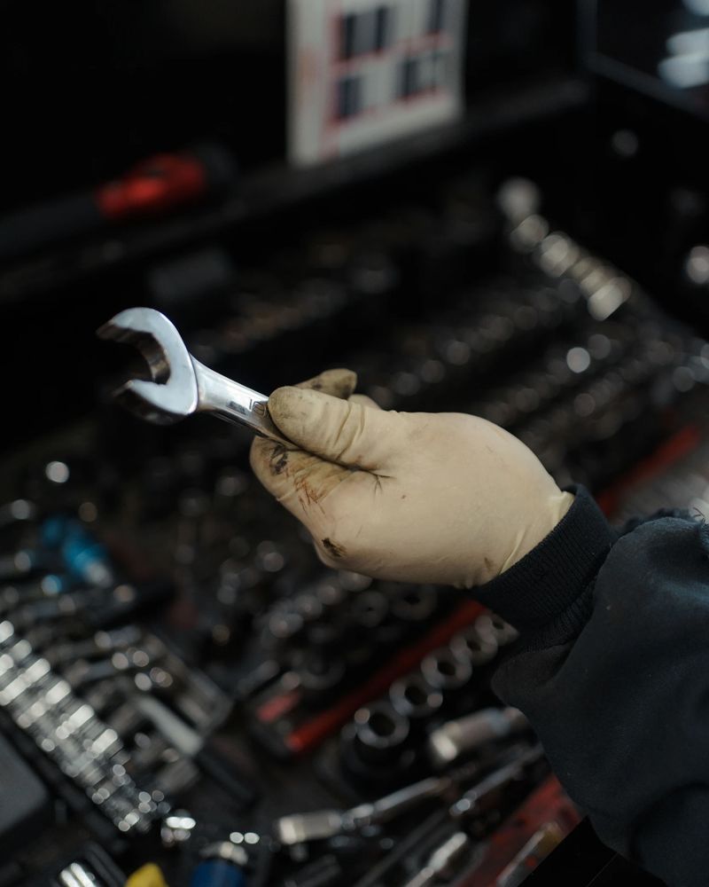 Gloved hand holding a combination wrench over the tool chest